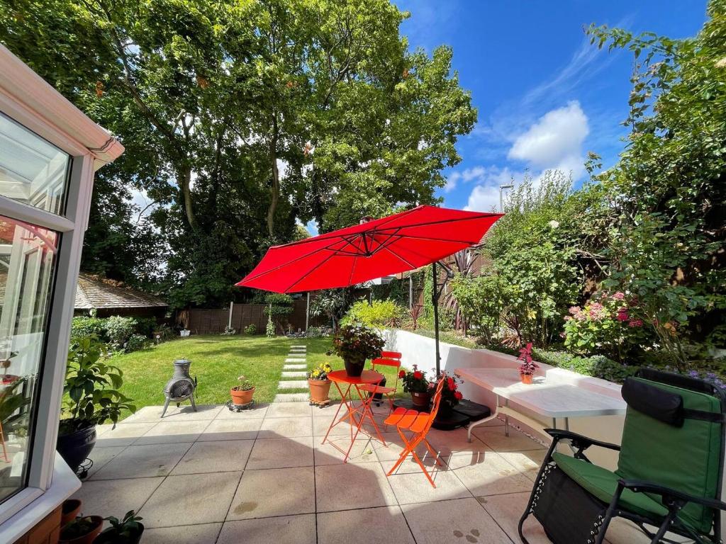 un patio con sombrilla roja, mesa y sillas en Comfortable. home from home en Loudwater
