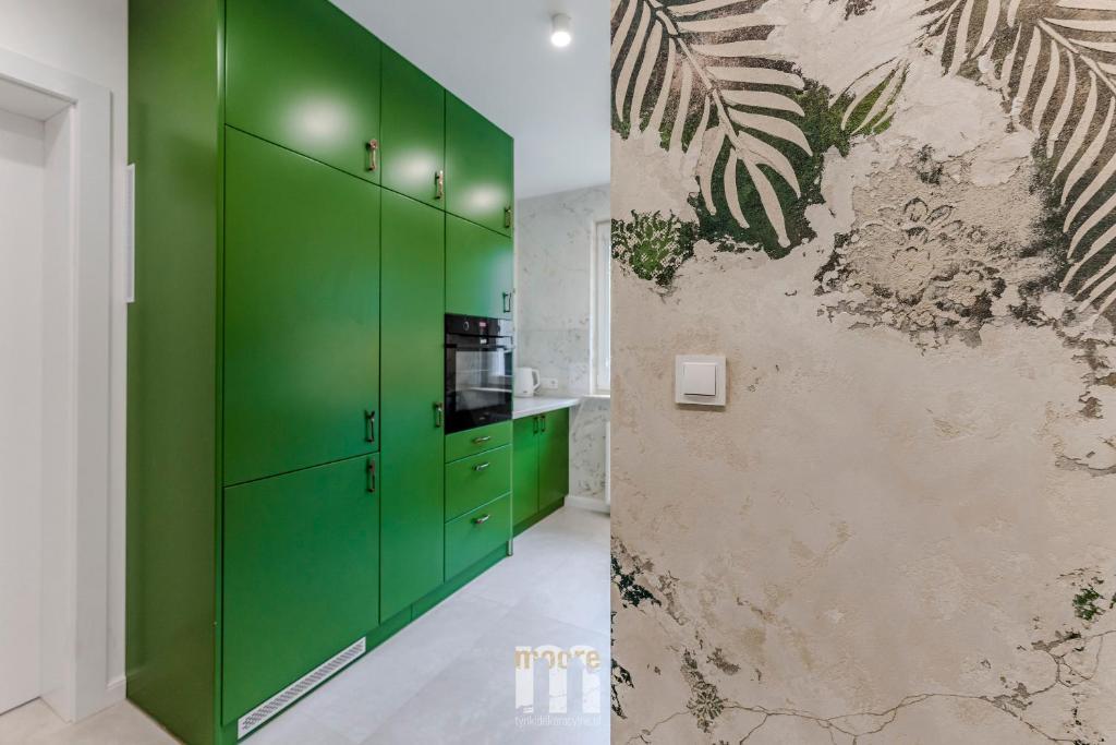 una cocina con armarios verdes y una pared en Tropical Jungle Apartament, en Otwock