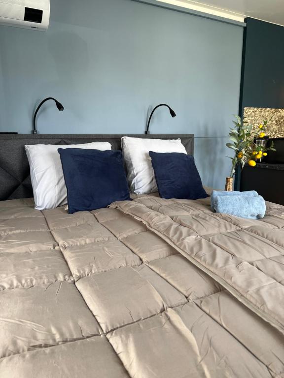 a large bed with blue and white pillows at B&B/Tiny House Bij Zee in Stellendam