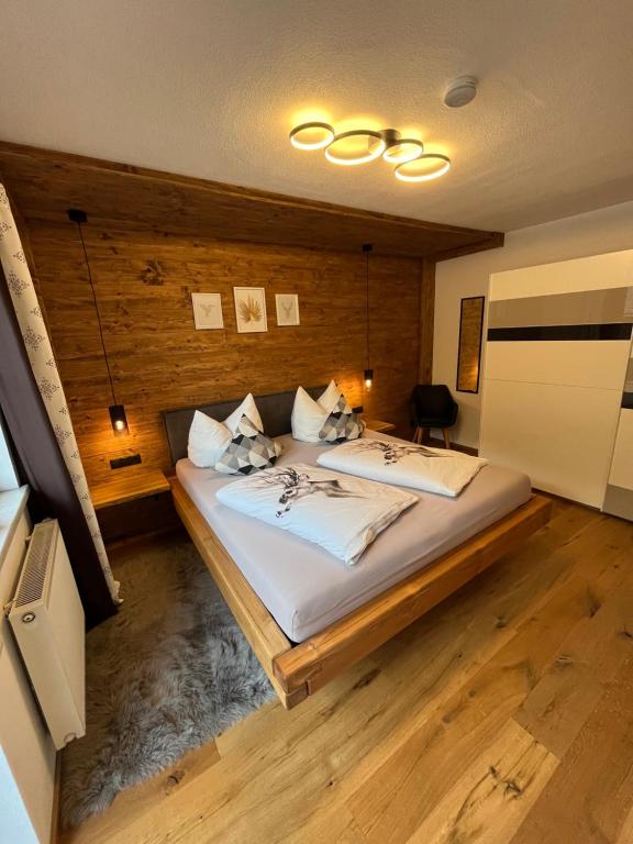 sypialnia z dużym łóżkiem i drewnianą ścianą w obiekcie Alpentime Apartments w Neustift im Stubaital