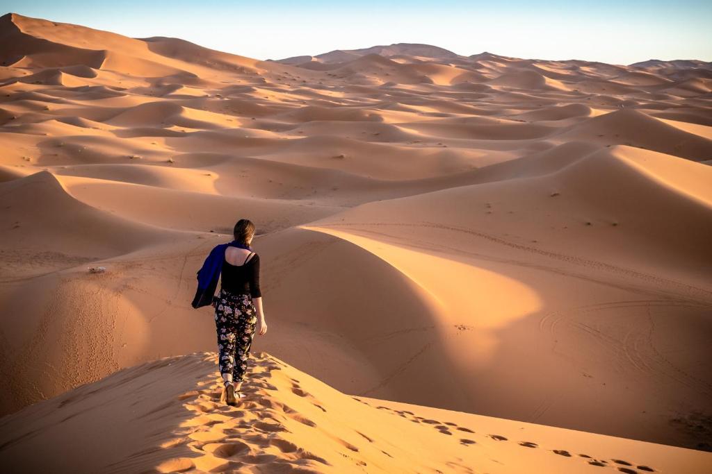 a woman walking on a sand dune in the desert at Nejma luxury camp erg chegaga in El Gouera