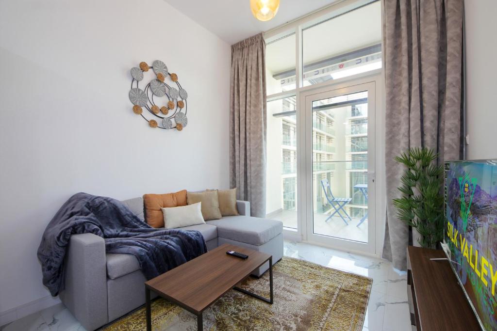 ein Wohnzimmer mit Sofa und Tisch in der Unterkunft Silk Valley - Cozy 1bhk With Pool And Gym in Abu Dhabi