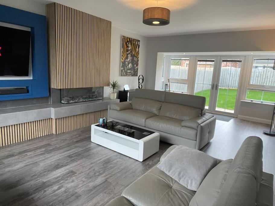 ein Wohnzimmer mit einem Sofa und einem TV in der Unterkunft Belfast Luxury: Spacious 2BR Home Near Stormont in Belfast
