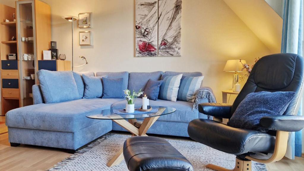 a living room with a blue couch and two chairs at Ferienwohnung Parkblick Nr. 23 in Kühlungsborn