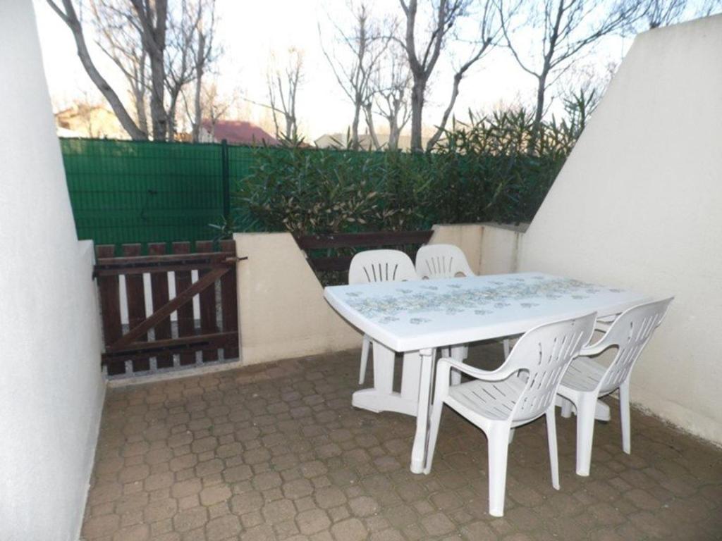 une table blanche et des chaises sur une terrasse dans l'établissement Studio RDC 4 couchages avec terrasse à Marseillan, proche plage, parking privé - FR-1-326-614, à Le Castellas