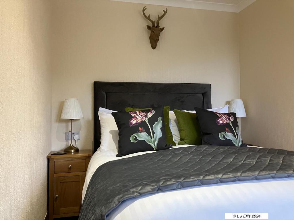 sypialnia z łóżkiem z poduszkami i głową jelenia na ścianie w obiekcie Foyers House w mieście Foyers