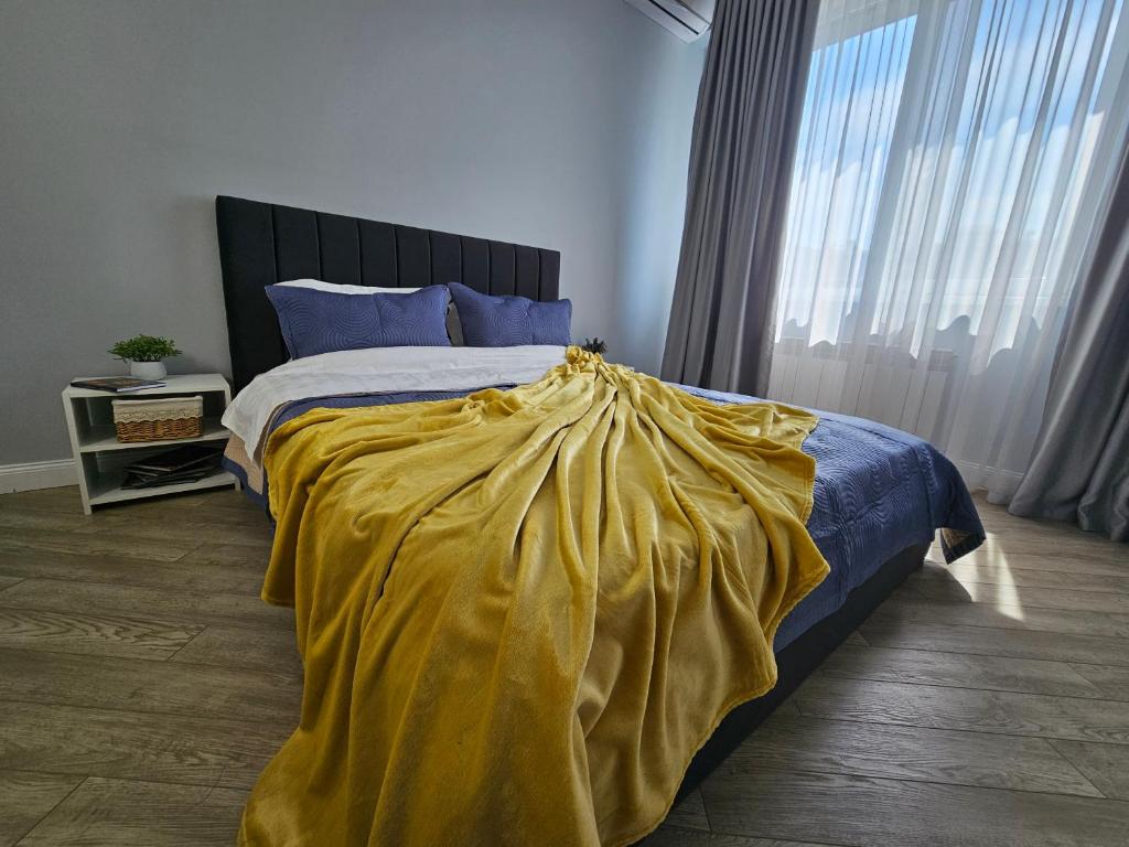 a bedroom with a bed with a yellow blanket on it at 3 room Gagarin Park Residential Complex near MEGA Shopping Mall in Almaty