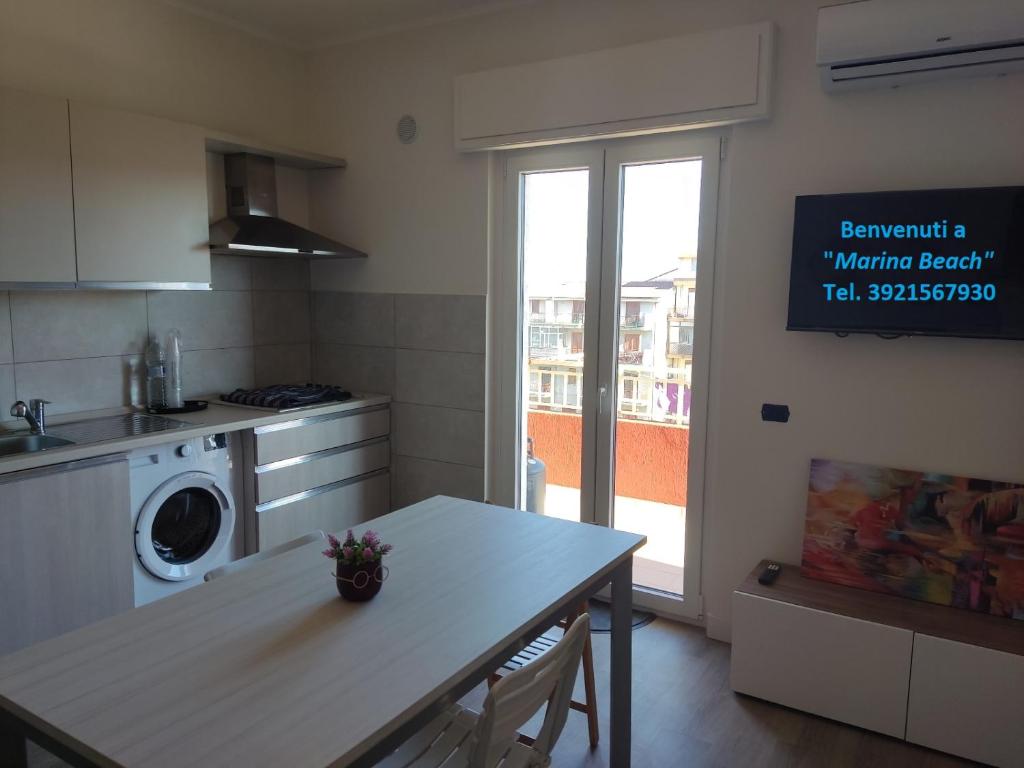cocina con mesa y lavadora en Sunrise Apartment Marina Beach, en Marina di Gioiosa Ionica