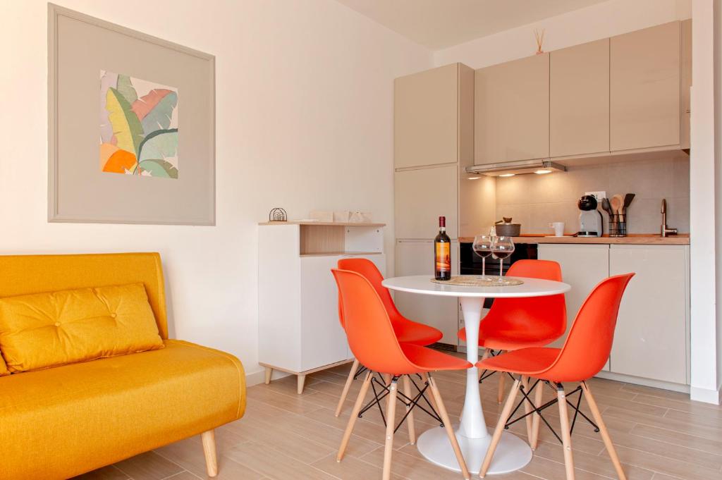 ein Wohnzimmer mit einem Tisch und orangefarbenen Stühlen in der Unterkunft Homiday- New Apt- Free Parking- Aeroporto - Ospedale in Pisa