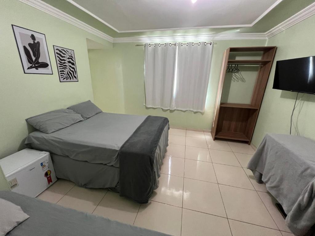 a bedroom with two beds and a television in it at DLUX Hotel in Campos dos Goytacazes