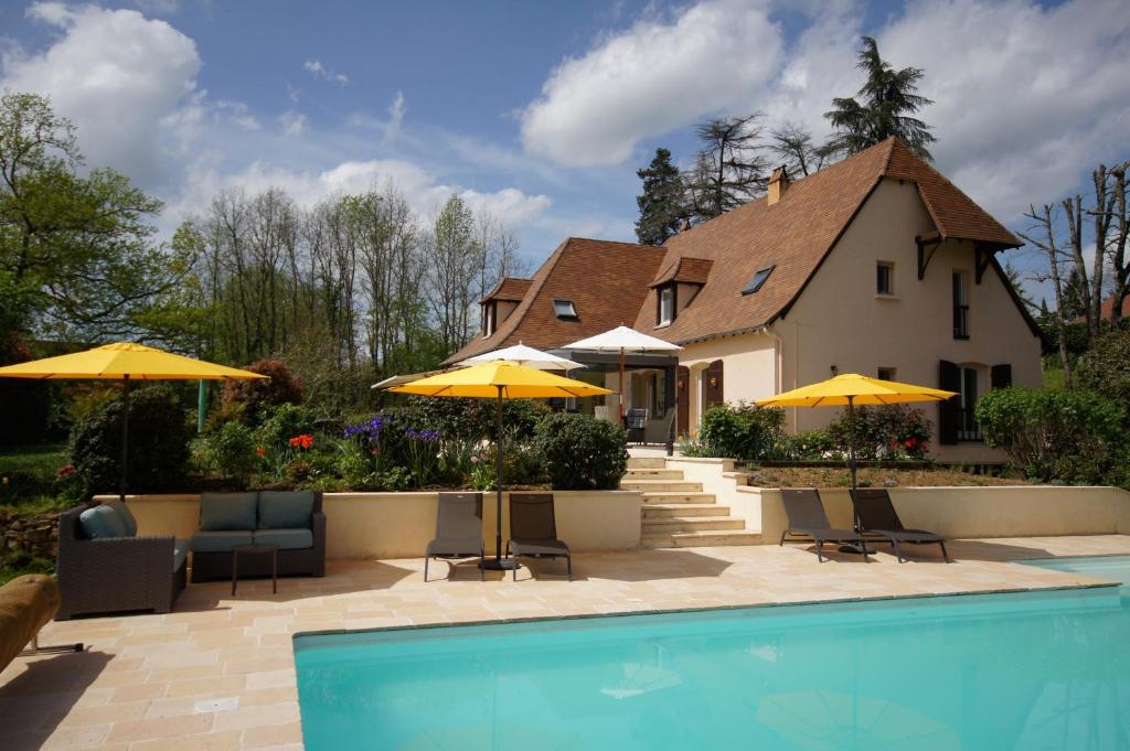 Chambres d'Hôtes La Bonne Voie في Lembras: بيت فيه مسبح ومظلات صفراء