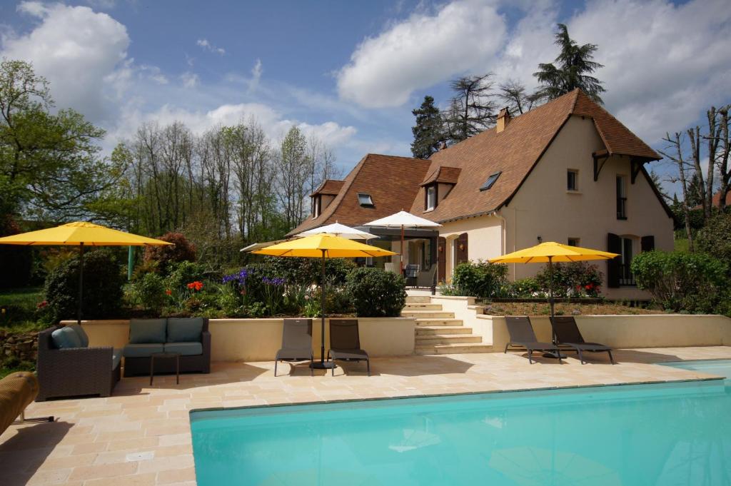 a house with a swimming pool and yellow umbrellas at Chambres d'Hôtes La Bonne Voie in Lembras