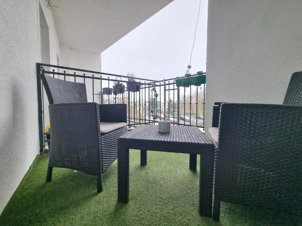 balkon z 2 krzesłami, stołem i poręczą w obiekcie Apartamenty Firfas 9 w Bydgoszczy