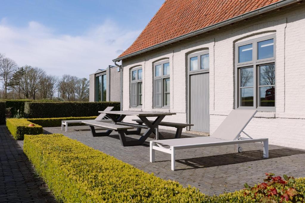 two picnic tables and a bench in front of a building at Spacious holiday home with indoor pool & sauna in Veurne