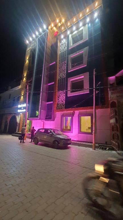 a pink building with a car parked in front of it at Hotel Aadhya & Resataurant in Auraiya