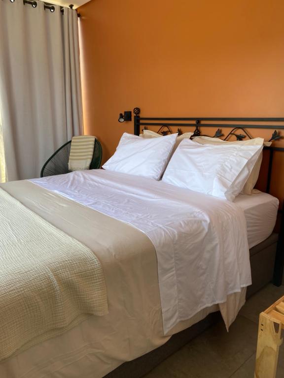 een bed met witte lakens en kussens in een kamer bij Janela Verde in Cidade Ocidental
