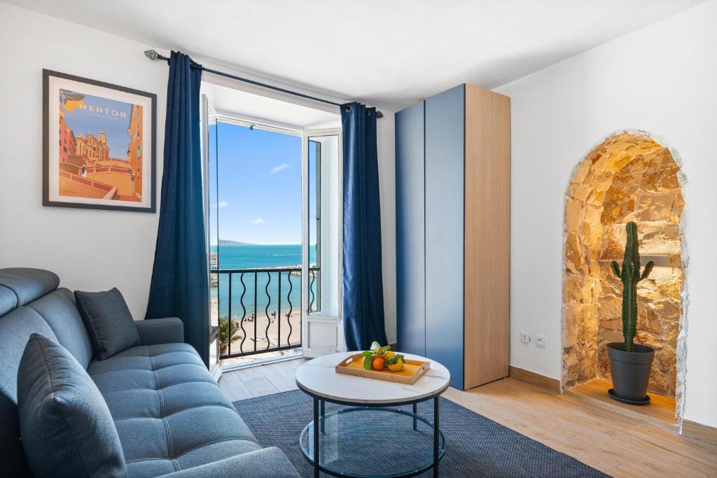 un salon avec un canapé et une grande fenêtre dans l'établissement Les Sablettes - Cosy studio vue mer, vieux Menton, à Menton