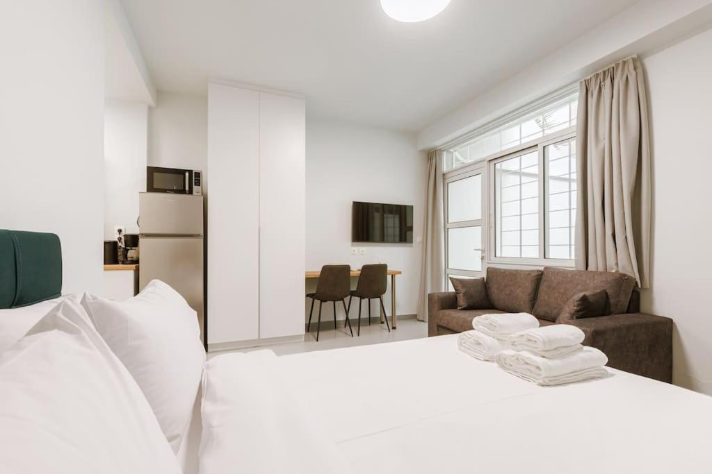 ein Schlafzimmer mit einem weißen Bett und einem Sofa in der Unterkunft Snug studio apartment with pvt garden access I in Athen