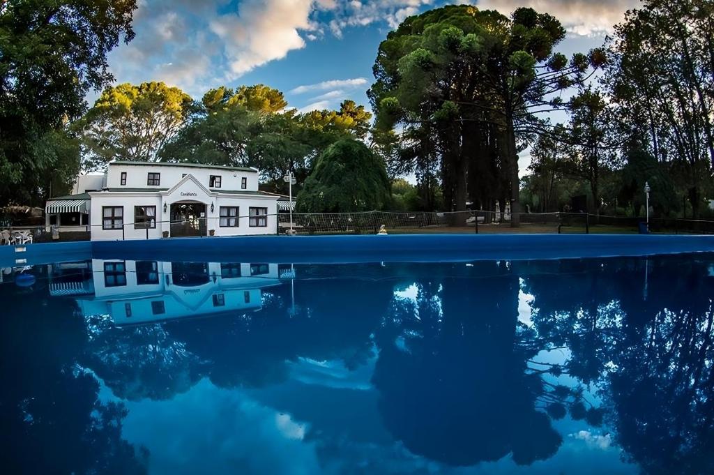 Una casa blanca se refleja en un estanque de agua. en Casablanca La Granja de Capilla, en Capilla del Monte