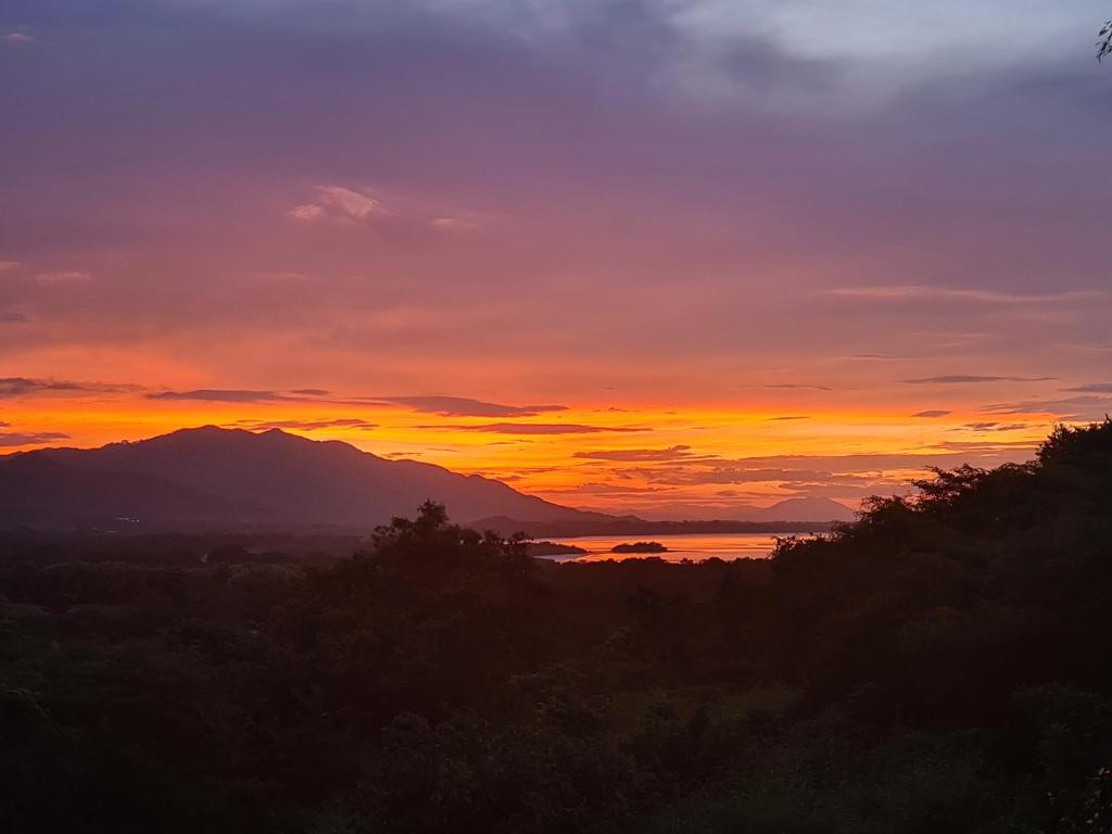 a sunset over a body of water and a mountain at La Casa del Conde in Playa Naranjo