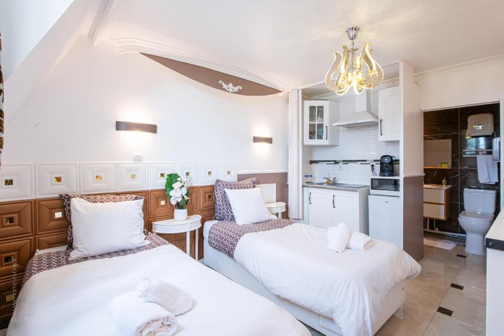 2 Betten in einem kleinen Zimmer mit Küche in der Unterkunft Studio Marron - Paris à 10 min - RER in Deuil-la-Barre