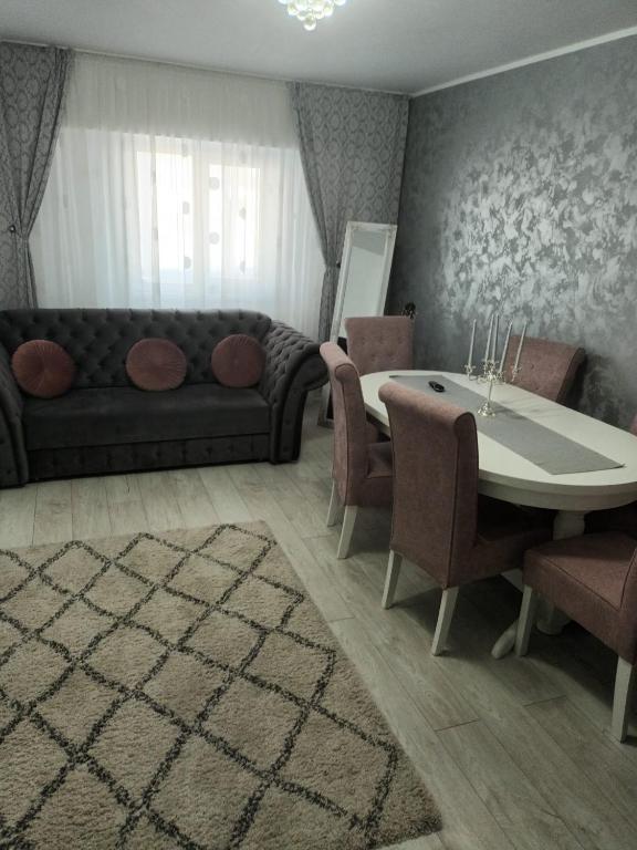 SorinaApartament1 في تارجو نيمت: غرفة معيشة مع أريكة وطاولة وكراسي