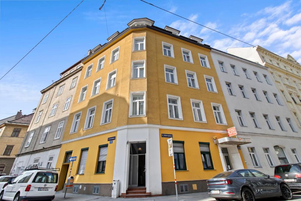 un edificio amarillo en una calle con coches aparcados delante en Designer Apartments Asaria en Viena
