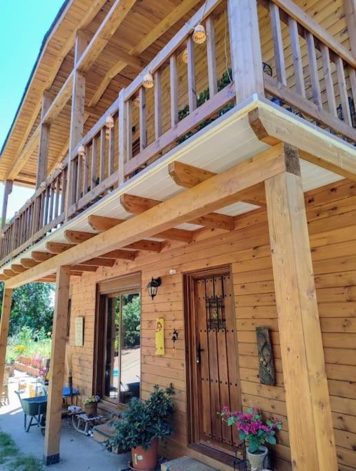 a large wooden house with a large wooden deck at Preciosa cabaña con jardín y barbacoa in Guadarrama