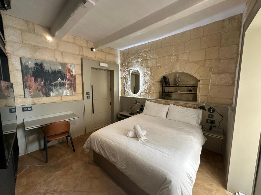 a bedroom with a white bed and a desk at Domingo x Casa Norte in Birgu