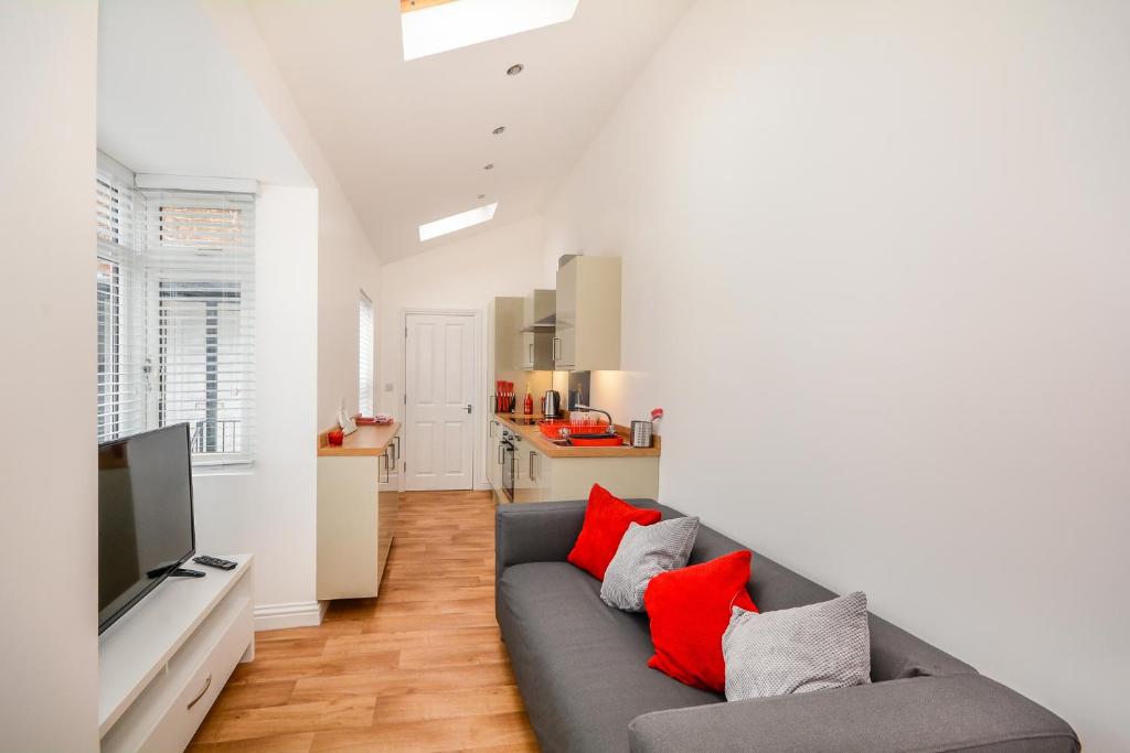 ein Wohnzimmer mit einem grauen Sofa und roten Kissen in der Unterkunft Henry Court Apartment 3 in York