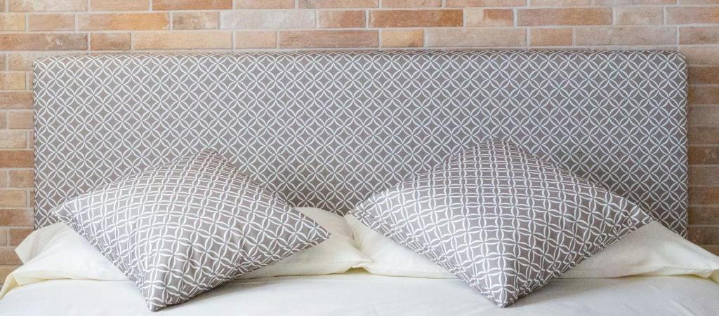 two pillows on a bed with a brick wall at Foresteria Lombarda GELSO BIANCO in Cogliate