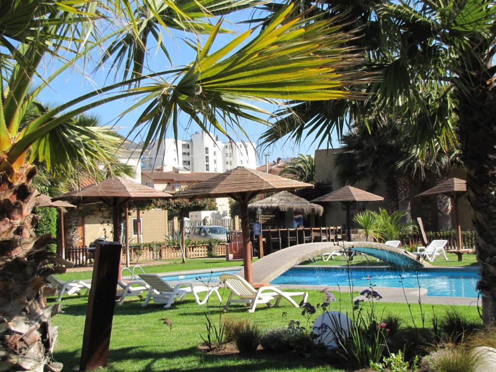 uma piscina com cadeiras e guarda-sóis num resort em Apart Hotel Gran Pacifico em La Serena