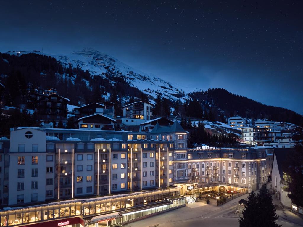 a hotel at night with a mountain in the background at Precise Tale Seehof Davos in Davos