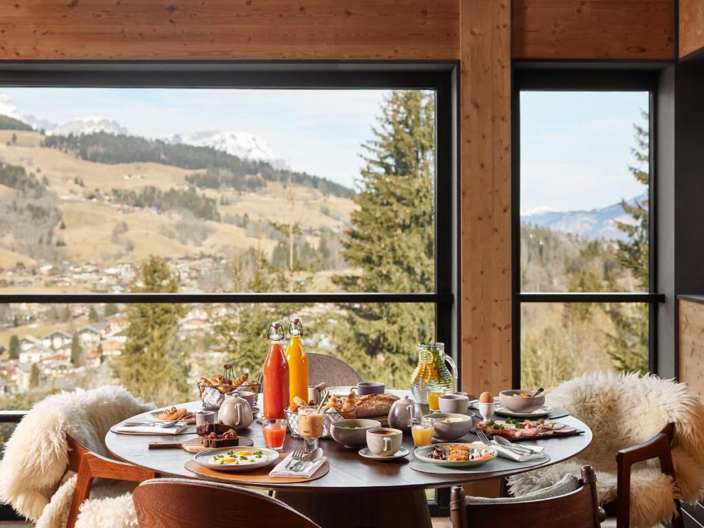 una mesa con comida delante de una ventana en Hôtel L'Arboisie en Megève