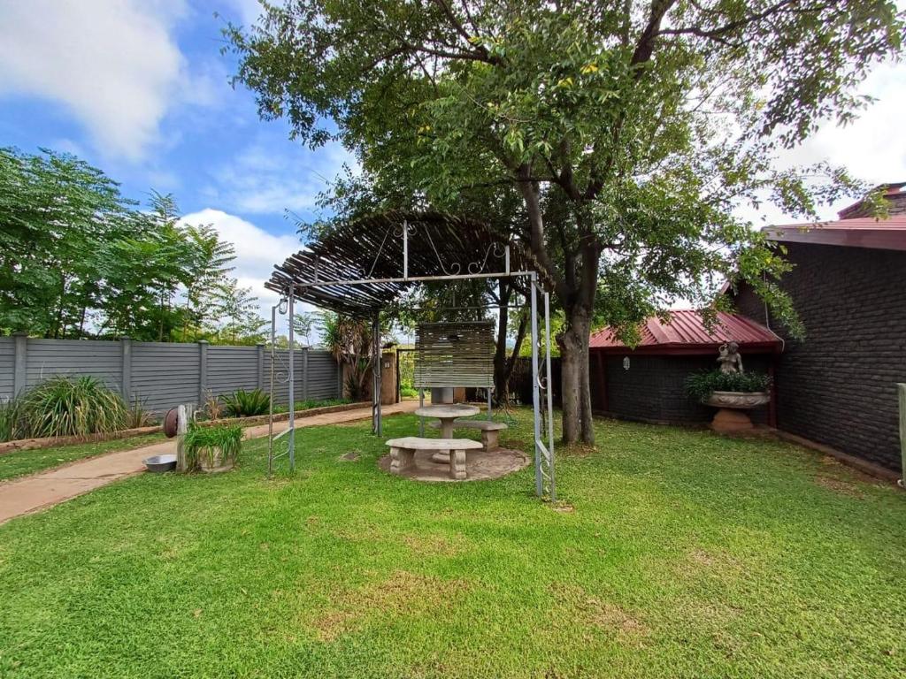 a park with a bench and a tree in a yard at At Ease Road Lodge in Zeerust