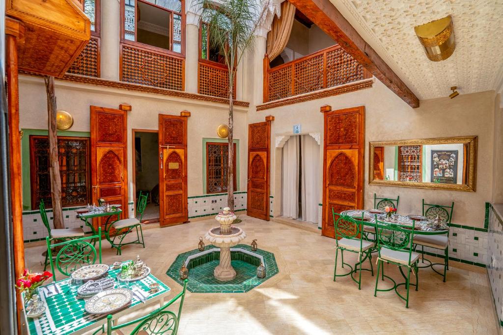 Habitación grande con mesas, sillas y una fuente. en Riad Chez Henriette en Marrakech