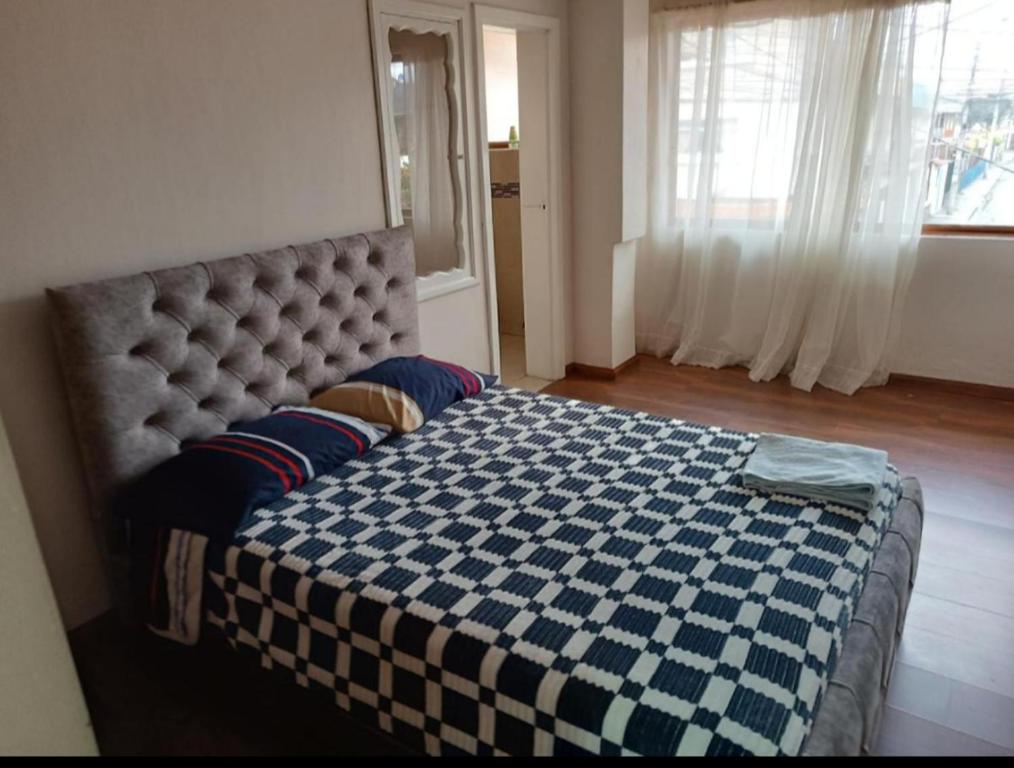 1 dormitorio con 1 cama blanca y azul a cuadros en Departamento Gigante de 4 dormitorios. Ecualodge 23, en Cuenca