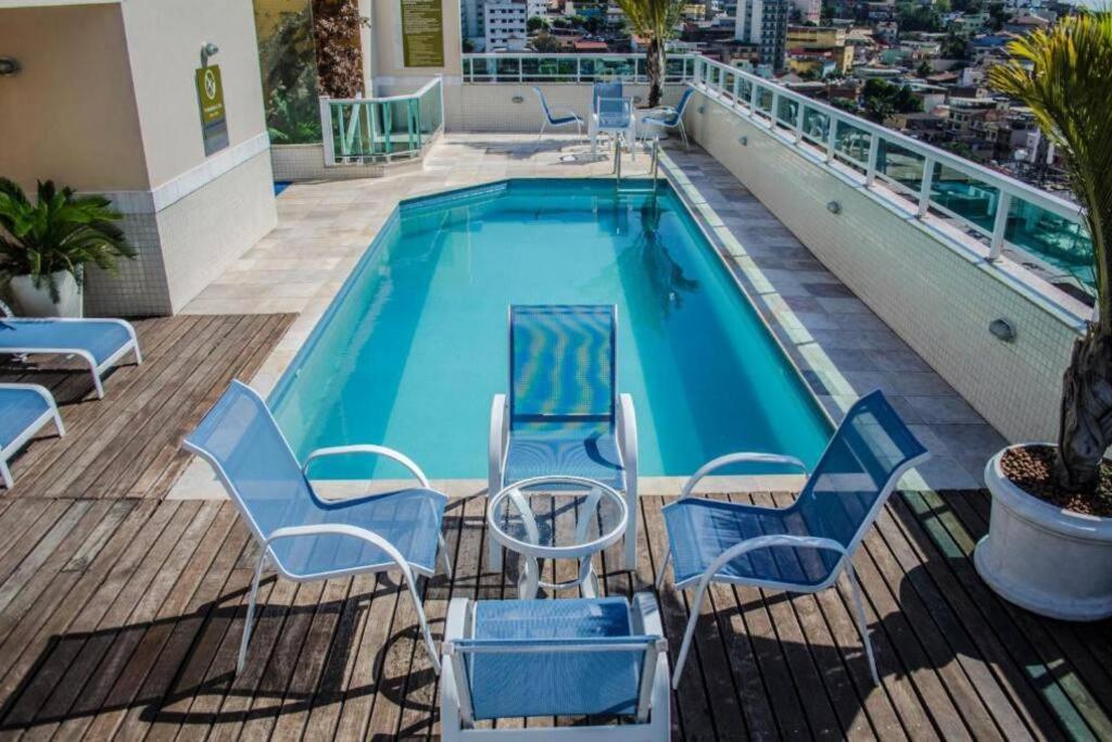 a swimming pool with chairs and a table on a balcony at Mont Blanc Apart Hotel Quarto 102 in Duque de Caxias