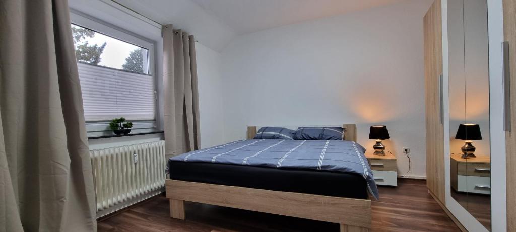 - une chambre avec un lit doté d'une couverture bleue et d'une fenêtre dans l'établissement Gemütliches Nest zum Wohlfühlen, à Osnabrück
