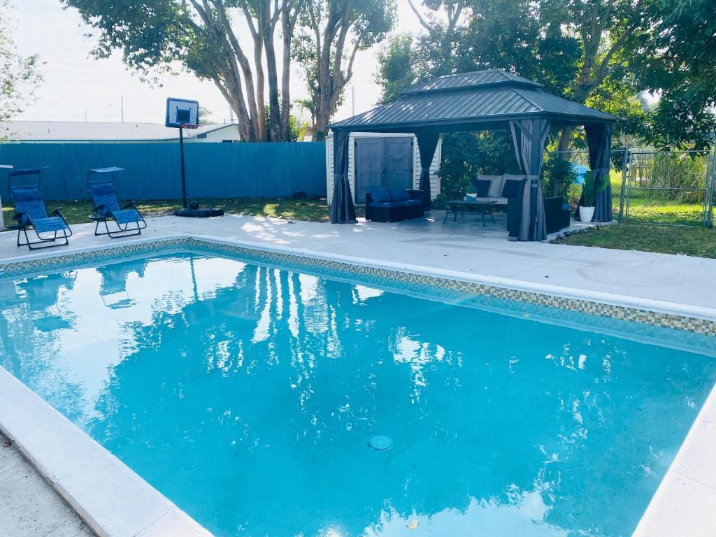 a swimming pool with chairs and a gazebo at Cottage in the Gardens! in Miami Gardens