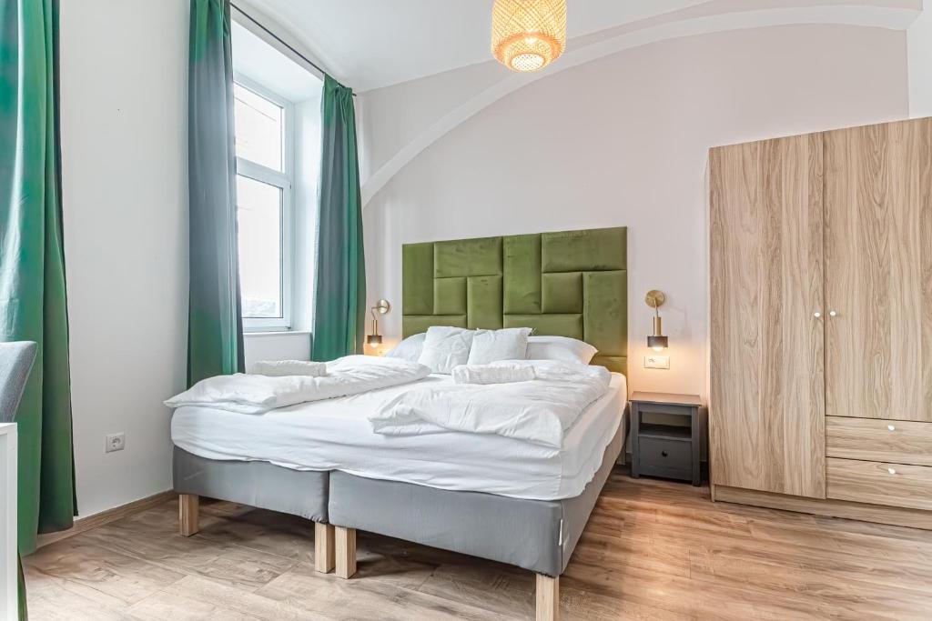 a bedroom with a large white bed with green accents at Westbahnhof Kingbed 1BR Apt with ensuite washer in Vienna
