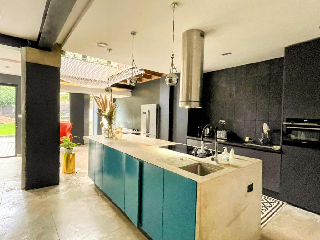 Remarkable 7-Bed House in London في لندن: مطبخ مع دواليب زرقاء ومغسلة