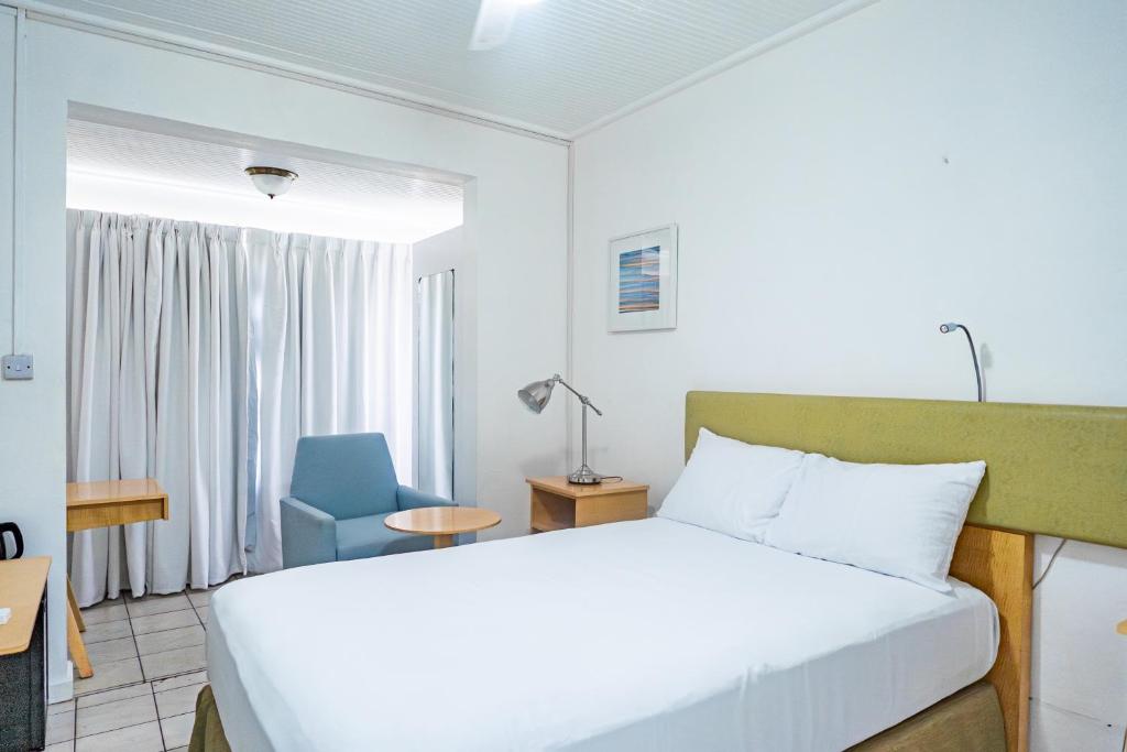 a bedroom with a bed and a blue chair at Ocean's Edge Lodge Restaurant & Bar in Roseau