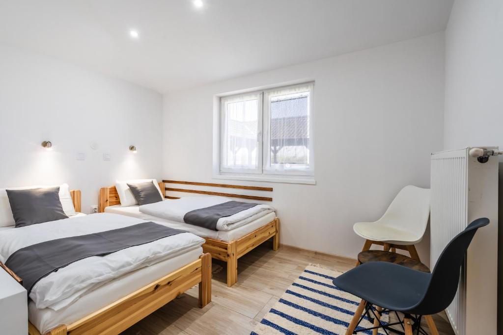 1 dormitorio con 2 camas y 1 silla en Alborella Vendégház, en Fadd