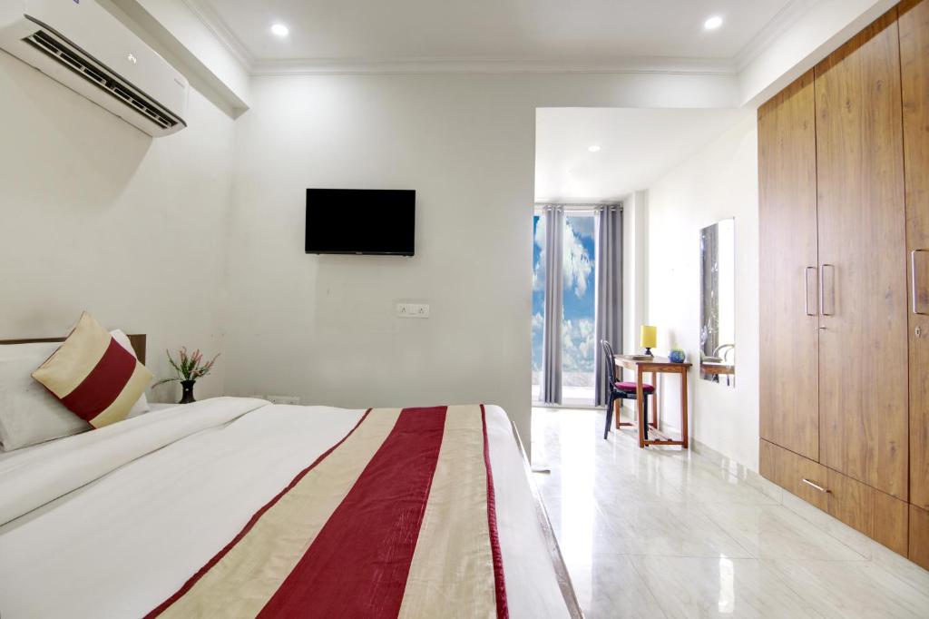 1 dormitorio con 1 cama grande y TV en la pared en Niketan Medanta Service Apartment - A BOUTIQUE HOTEL en Gurgaon