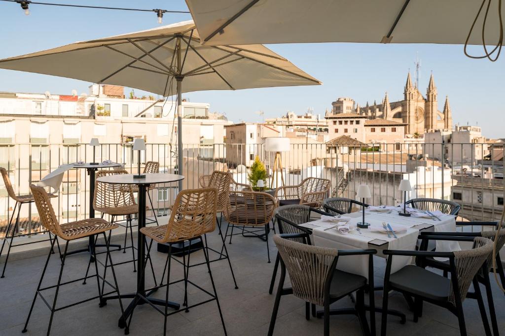 eine Terrasse mit Tischen, Stühlen und Sonnenschirmen in der Unterkunft Nivia Born Boutique Hotel in Palma de Mallorca
