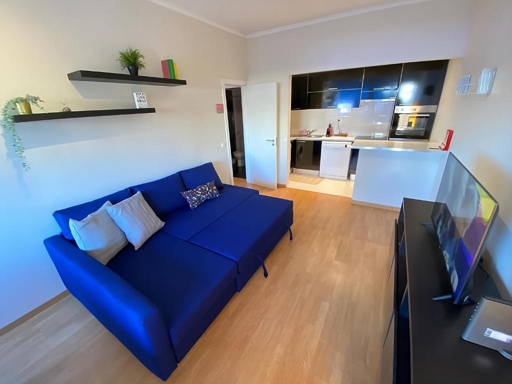 a living room with a blue couch and a kitchen at Columbano's House - Apartment in Central Lisbon in Lisbon