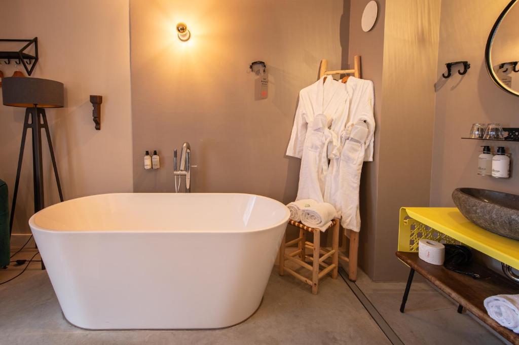 een badkamer met een groot wit bad en een wastafel bij Boutiquehotel The Church in Arnhem