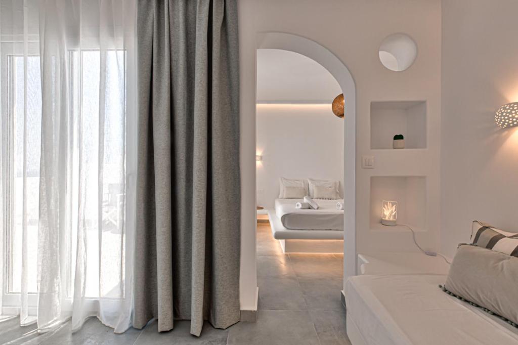 a white room with a bed and a mirror at Paros Blue Dolphin FULLY RENOVATED by RIVEA GROUP in Chrissi Akti