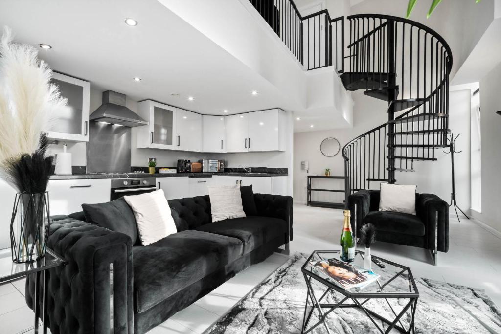 a living room with a black couch and a kitchen at Duplex Penthouse Apartment - Birmingham City Centre - Secure Parking - Terrace 1401M in Birmingham